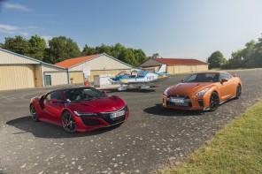 Honda NSX rouge vs Nissan GT-R orange devant un avion