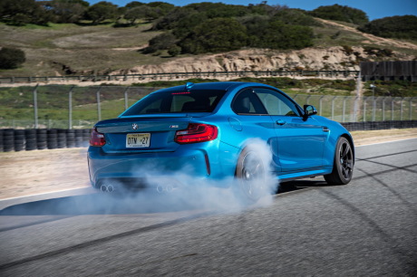 BMW M2 bleu 2016 faisant un brun sur circuit vue arrière