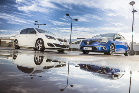 Renault Mégane GT 2016 bleu garée près d'une Peugeot 308 GT blanche avec leur reflet dans une flaque d'eau