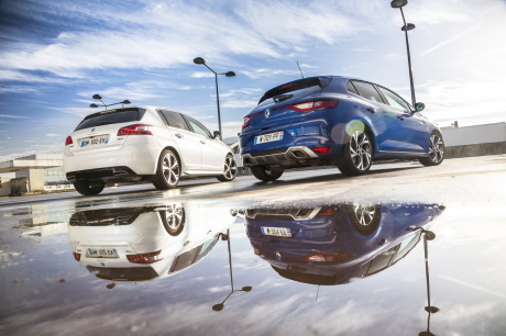 Renault Mégane GT 2016 bleu garée près d'une Peugeot 308 GT blanche avec leur reflet dans une flaque d'eau vue arrière