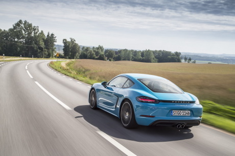Porsche Cayman 987 facelift bleu dans un virage vue arrière gauche