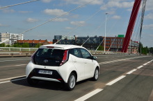 Toyota Aygo blanche 5 portes 2016 roulant sur une route vue arrière droite