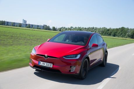 Tesla Model X 2016 rouge roulant sur une route de campagne vue avant gauche