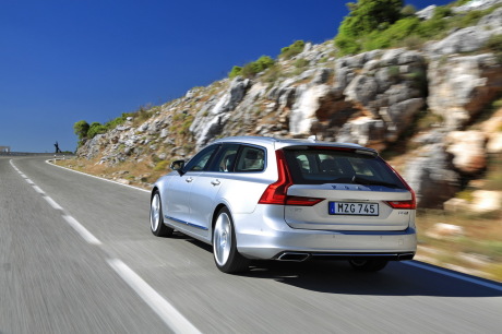 Volvo V90 2016 gris roulant sur une route de montagne vue arrière gauche