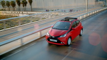 Toyota Aygo rouge 5 portes x-wave 2016 roulant sur une route vue avec le toit ouvert