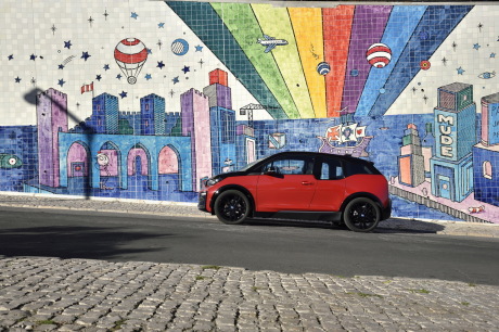 BMW i3s rouge de profil devant un mur tagué