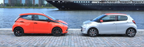 Citroën C1 grise garée à coté d'une Toyota Aygo orange au bord de l'eau vue de profil