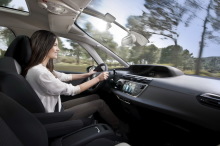Femme conduisant un Citroën C4 Picasso sous le pare-brise panoramique