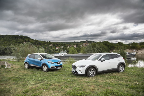 Essai comparatif entre un Renault Captur 2015 Intens bleu et un Mazdca CX-3 Dynamique blanc stationnés sur l'herbe